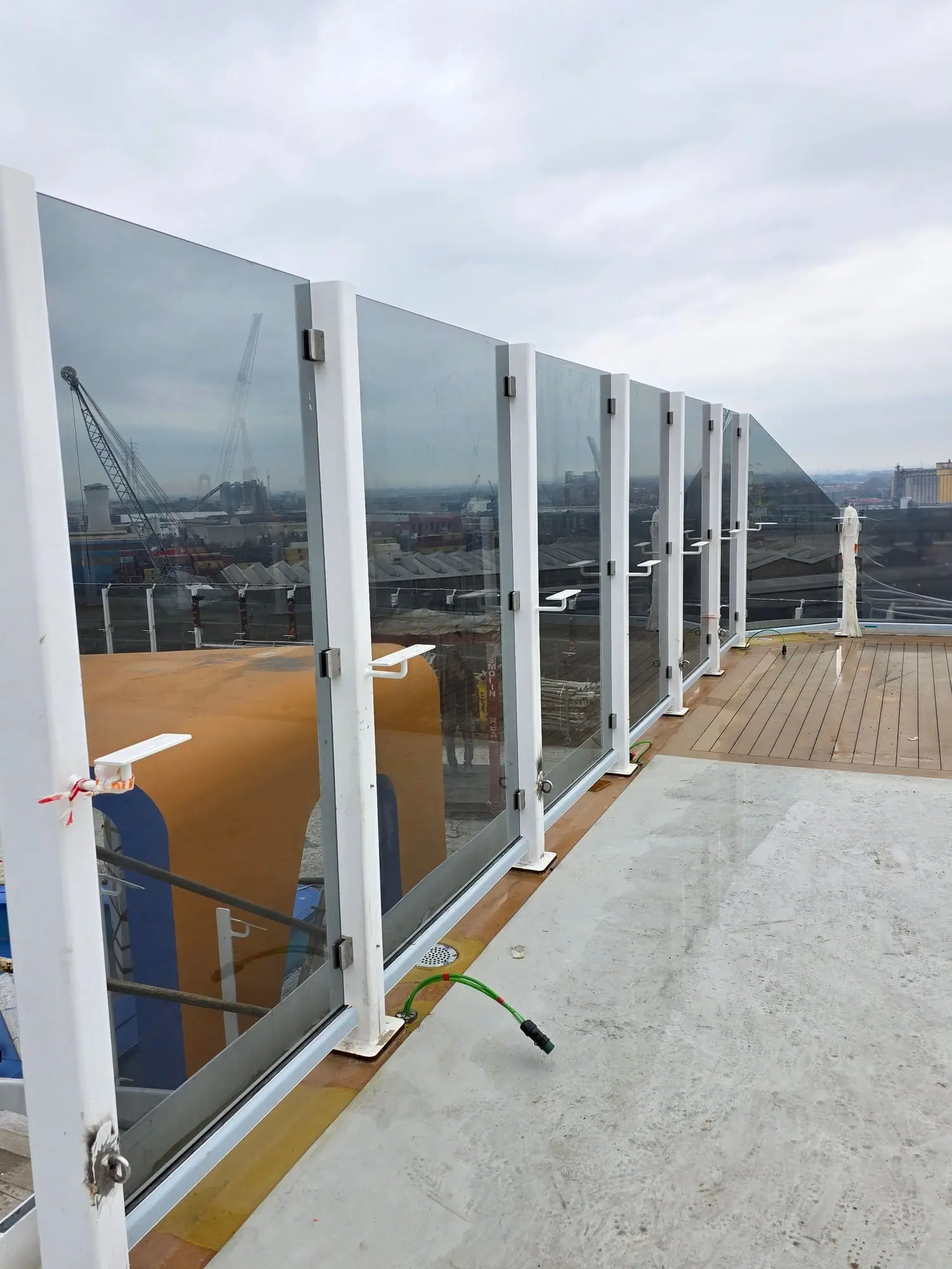 Balustradă dreaptă din sticlă între stâlpi albi din oțel, pe o punte deschisă