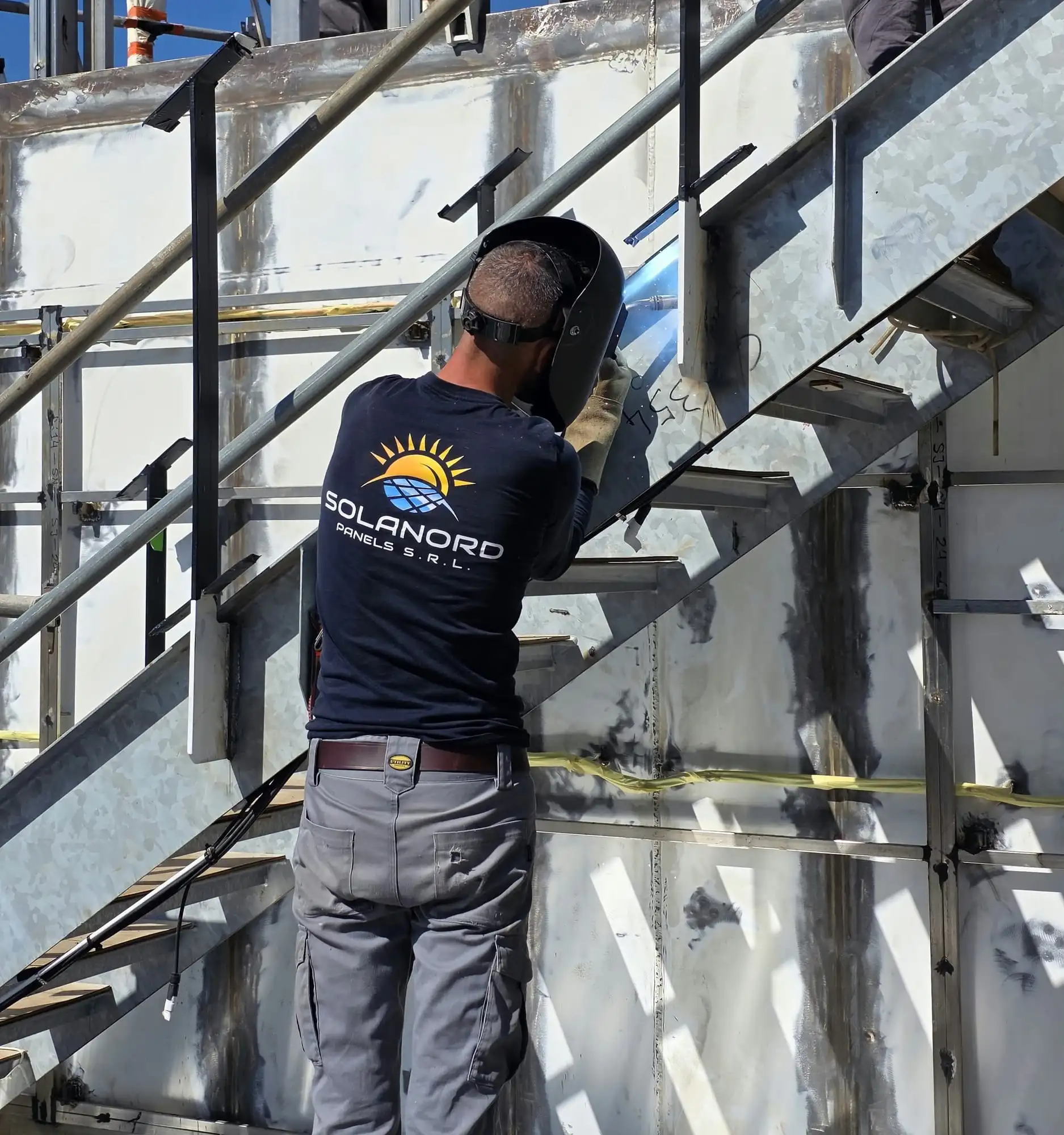 Sudor cu sigla Solanord pe spate, la un stâlp de balustradă al unei scări metalice