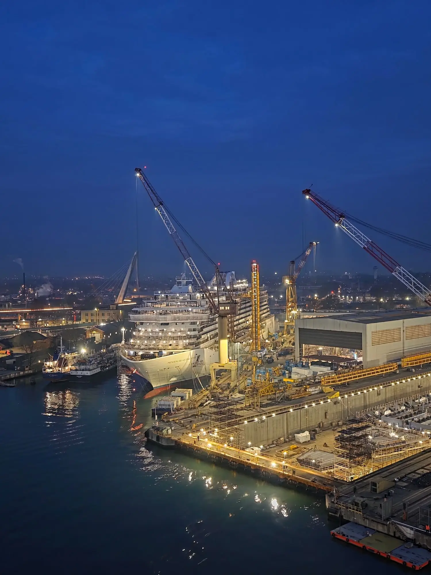 Seven Seas Prestige și șantierul, luminate, sub un cer întunecat